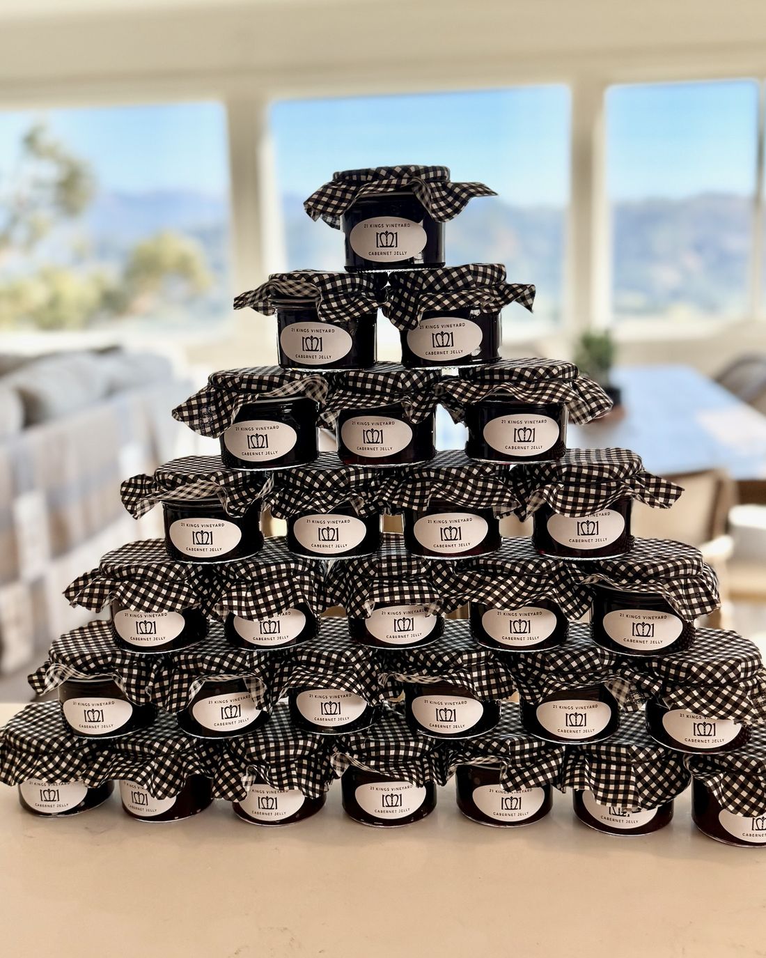 A pyramid of 21 Kings Vineyard Cabernet Jelly jars with black-and-white gingham tops